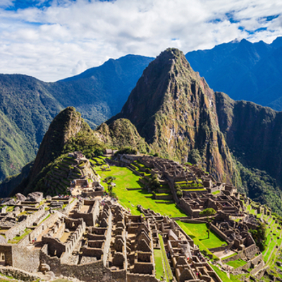 Machu Picchu in Peru met groene terrassen en bergen op de achtergrond.