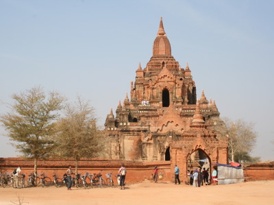 Bakstenen tempel in Bagan, Myanmar, met bezoekers en fietsen bij de ingang.