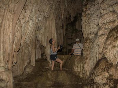Bezoekers verkennen een grot met stalactieten en stalagmieten tijdens de Route Guatemala, 21 dagen.
