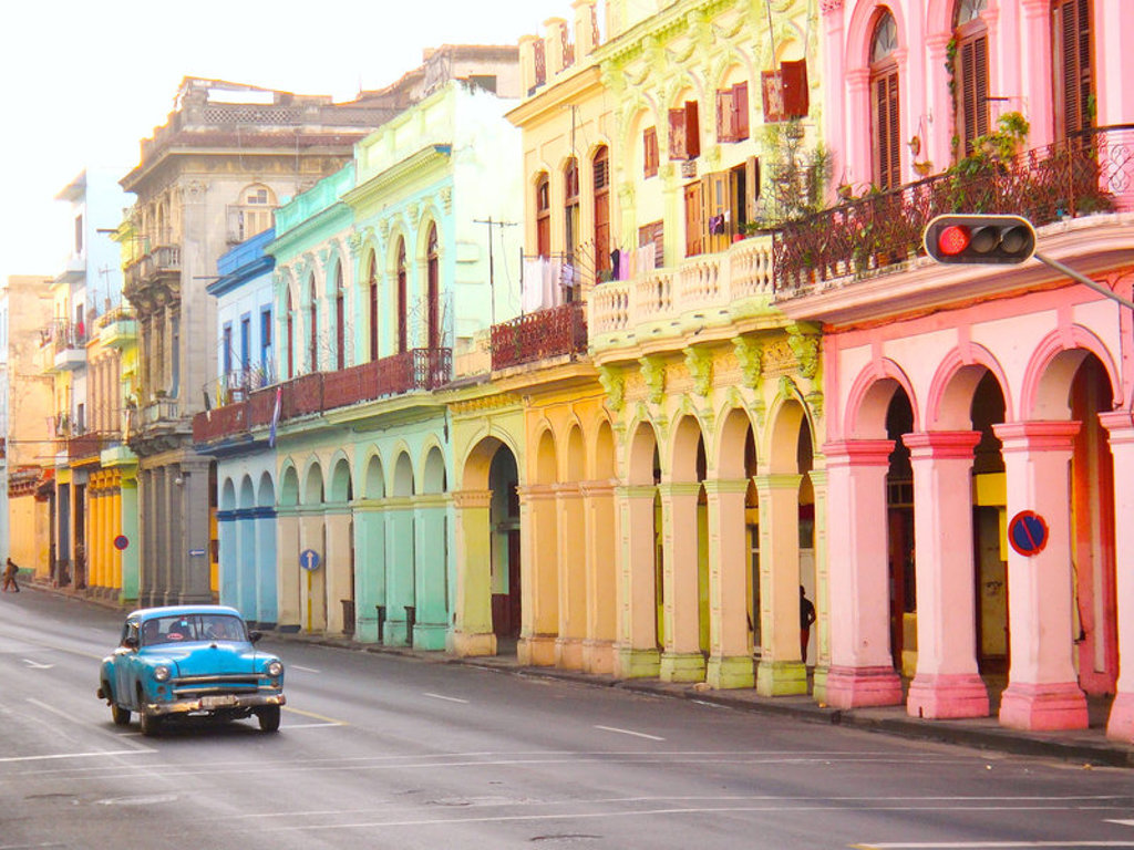 Kleurrijke straat in Havana met koloniale gevels en een klassieke blauwe auto, tijdens een familiereis Cuba.