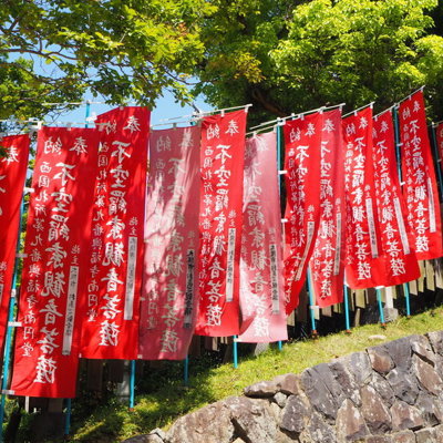 Rode Japanse tempelvlaggen met witte tekens langs een pad, tijdens groepsrondreis Japan Hoogtepunten.