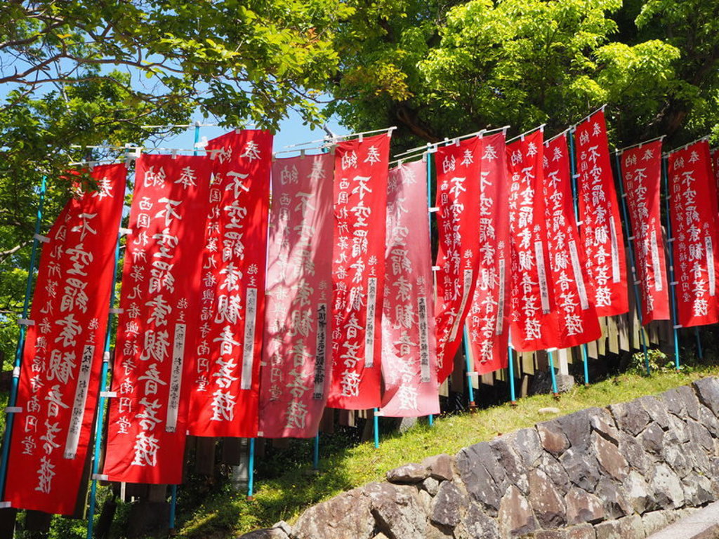 Rode Japanse tempelvlaggen met witte tekens langs een pad, tijdens groepsrondreis Japan Hoogtepunten.