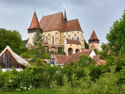 Burchtkerk van Biertan in Transsylvanië, Roemenië, met rode daken en torens tussen groen.
