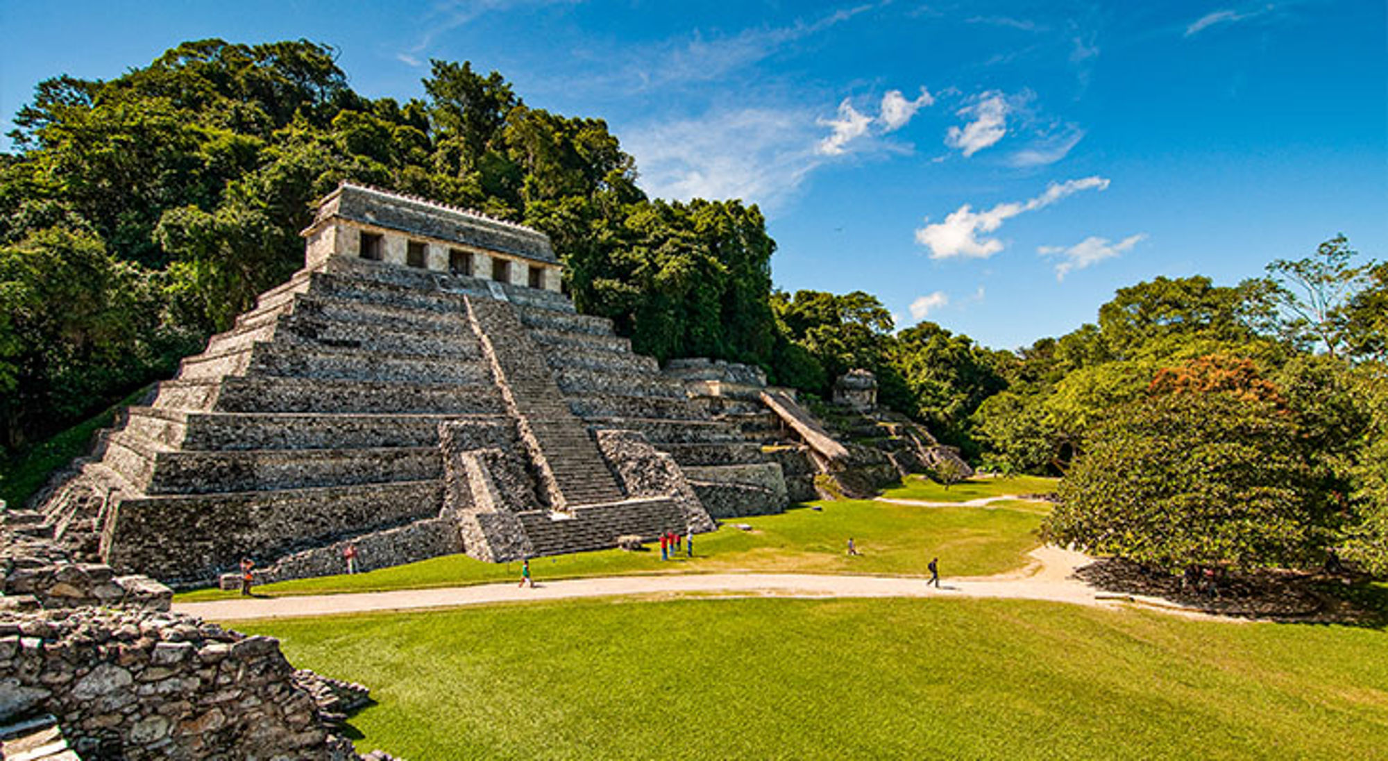 Palenque Maya-tempel van Palenque in Chiapas, Mexico, omringd door jungle en groene grasvelden.