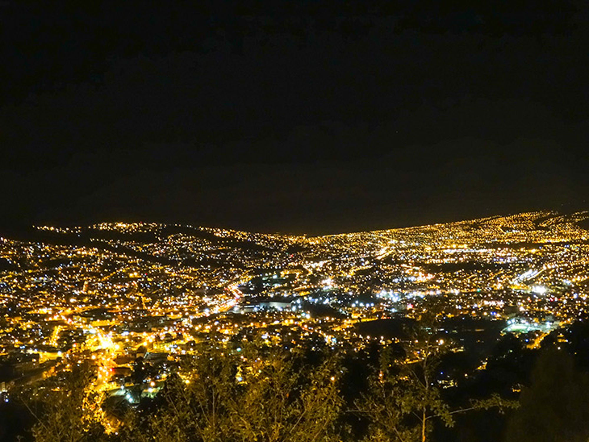 Quito in de avond Panoramisch uitzicht op een stad bij nacht met duizenden lichtjes en verlichte wegen in een heuvelachtig landschap.