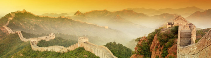 Grote Muur van China bij zonsopkomst, kronkelend over groene heuvels.