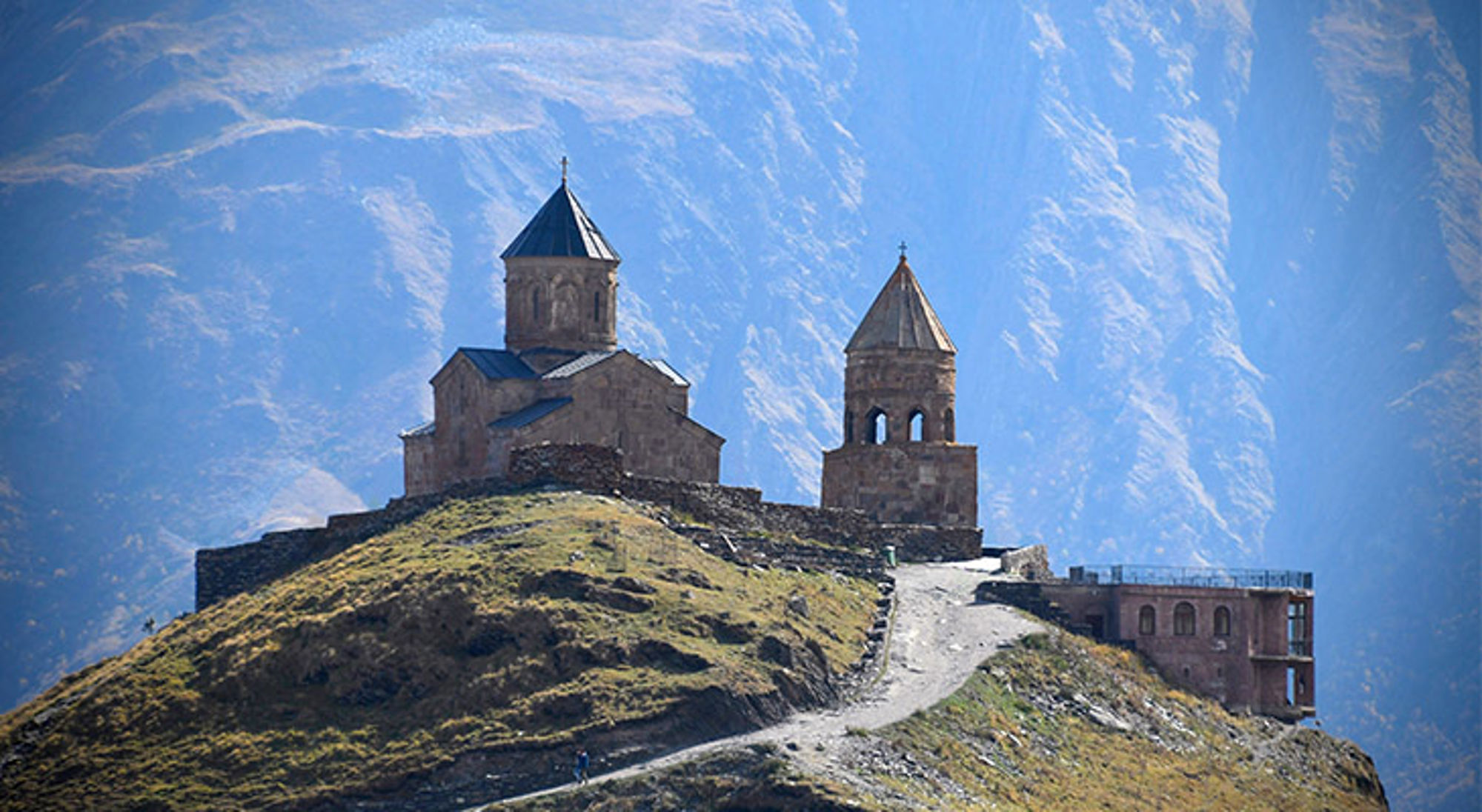 Gergeti Trinity Church in Stepantsminda Gergeti Drievuldigheidskerk op een heuveltop in de Kaukasus, met berglandschap op de achtergrond.