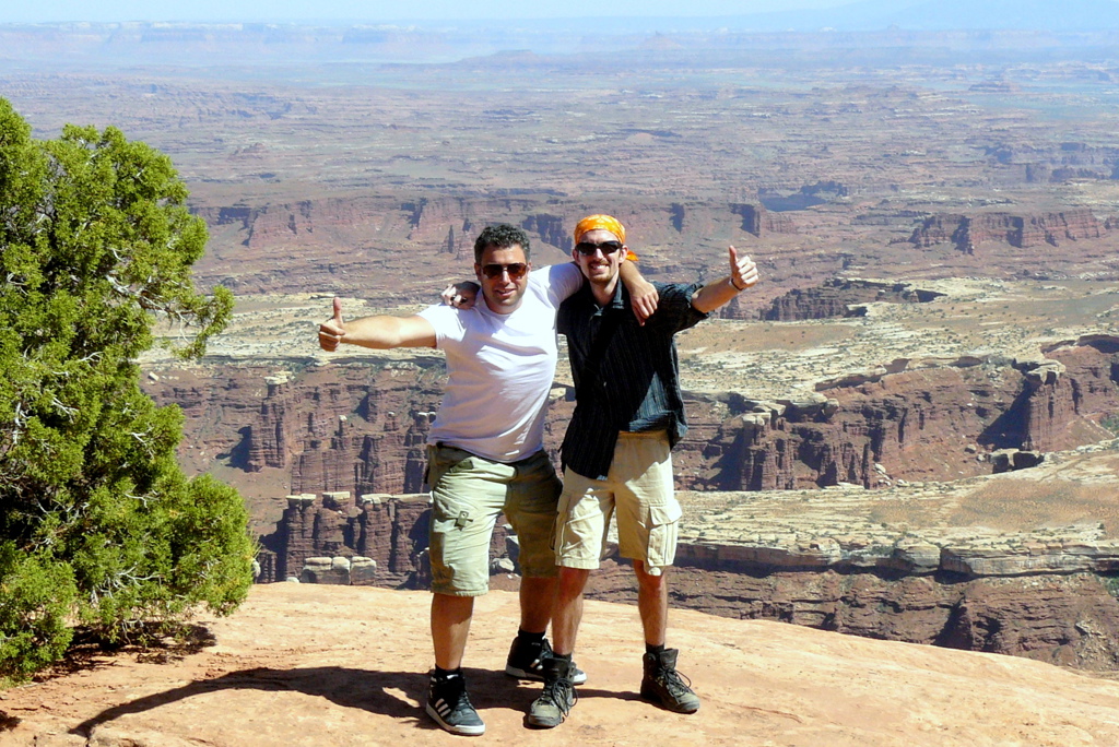 Twee reizigers poseren met duim omhoog bij een uitzichtpunt over Canyonlands in het westen van de Verenigde Staten.
