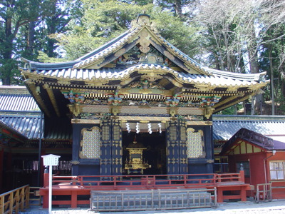 Rijk versierde tempelhal in Japan met goudaccenten en houten details, omringd door bomen.