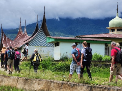 Wandelaars bij Minangkabau-huizen en een moskee in de bergen van Sumatra tijdens de route Sumatra, Java en Bali.