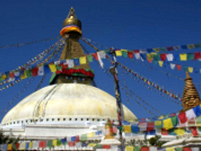 Boudhanath-stoepa in Kathmandu met kleurrijke gebedsvlaggen tegen een blauwe lucht.