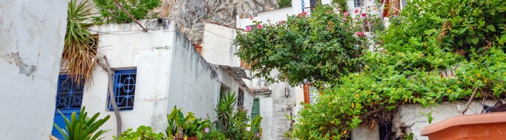 Witgekalkte straat in Anafiotika, Athene, met bloemen en uitzicht op de Akropolis.