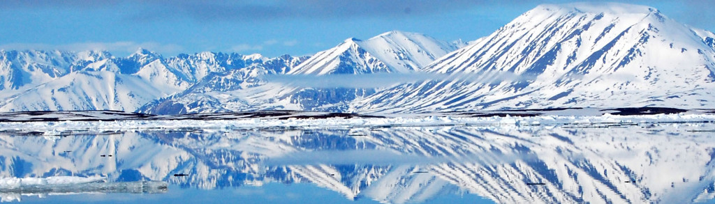 Besneeuwde bergen en drijvend zee-ijs bij Spitsbergen, weerspiegeld in kalm water.