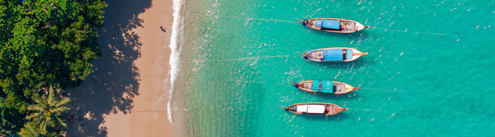 longtailboten voor een tropisch strand met helderblauw water in Thailand.