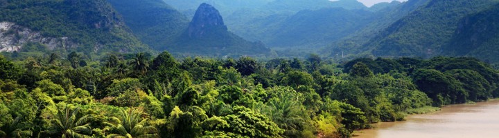 Groene jungle en bergen langs de rivier Khwae Yai in Thailand, met drijvend huisje aan de oever.