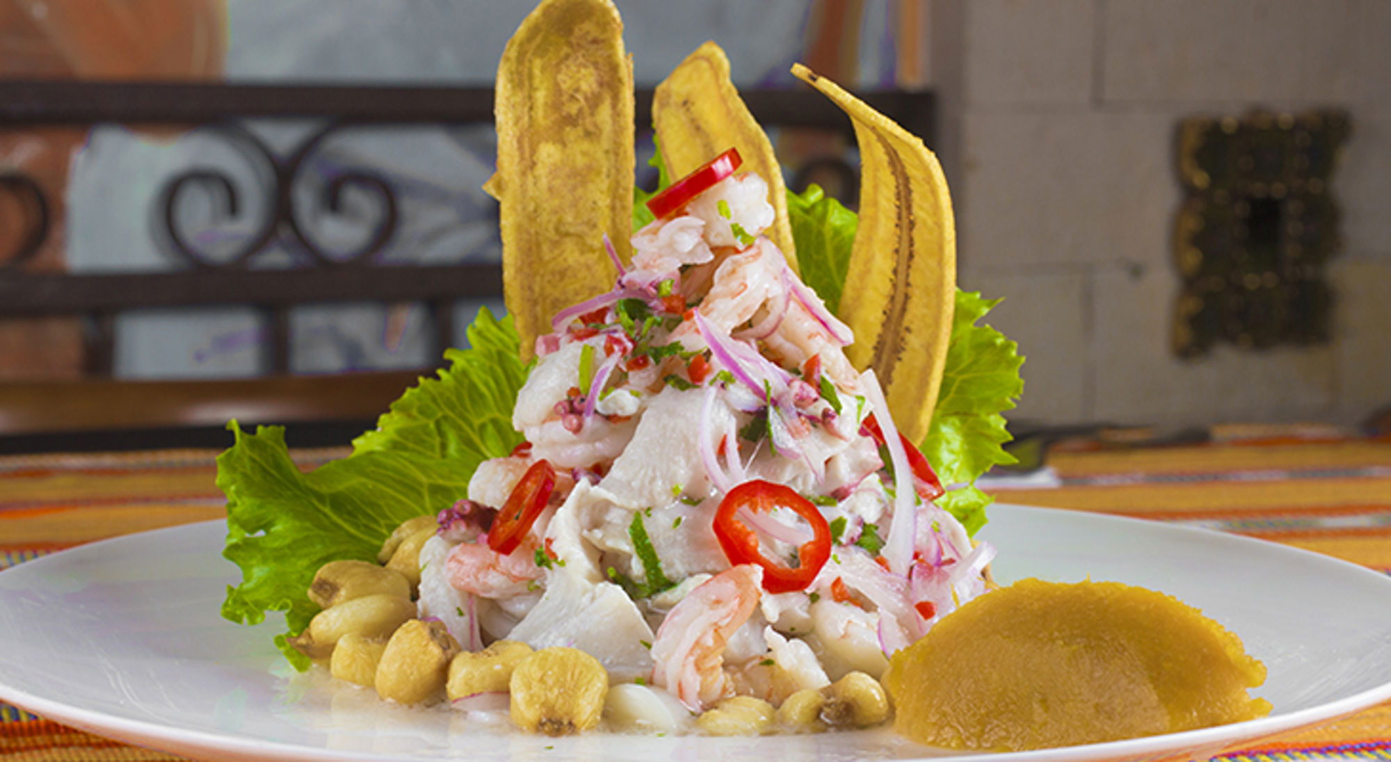 Ceviche met garnalen, rode ui en chilipeper, geserveerd met bakbanaan en sla.