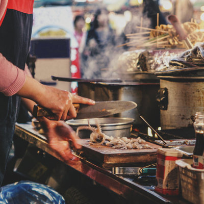 Streetfoodkraam in Zuid-Korea met kok die ingrediënten snijdt en kookt in grote pannen.