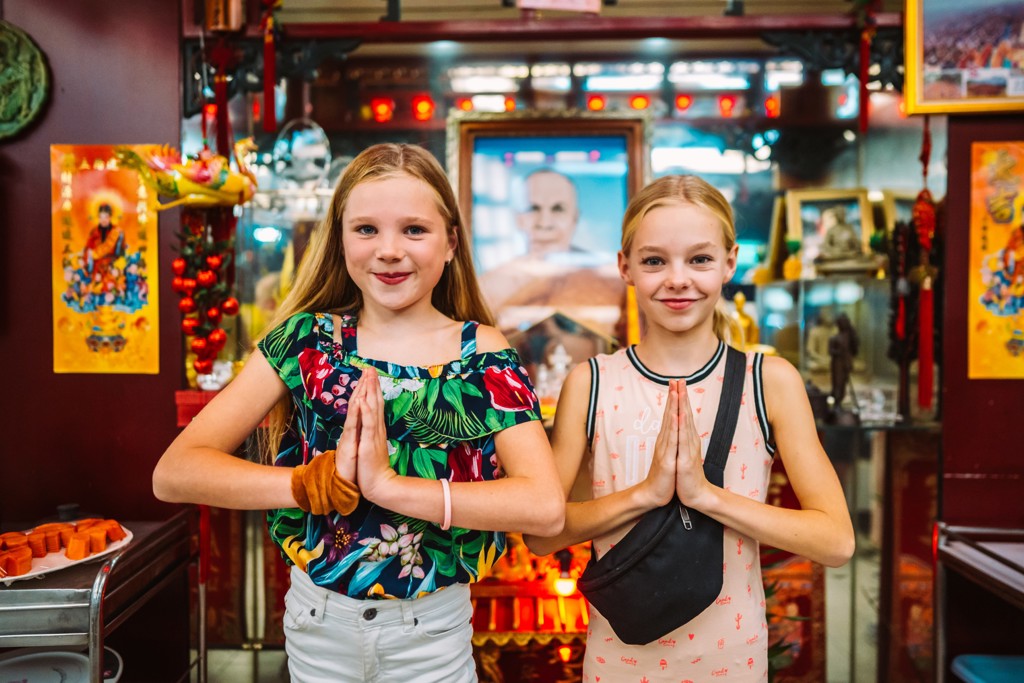 Kinderen brengen een wai-groet in een Thaise tempel tijdens een familiereis Thailand.