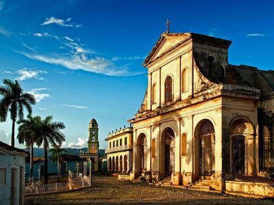 Kerk en palmbomen op het Plaza Mayor in Trinidad, Cuba, tijdens de rondreisroute.