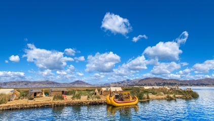 Rieteilanden en traditionele boot op het Titicacameer in Peru, met bergen op de achtergrond.