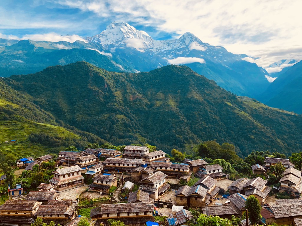 Nepalees bergdorp met traditionele huizen en uitzicht op de besneeuwde Himalaya tijdens een familiereis Nepal.