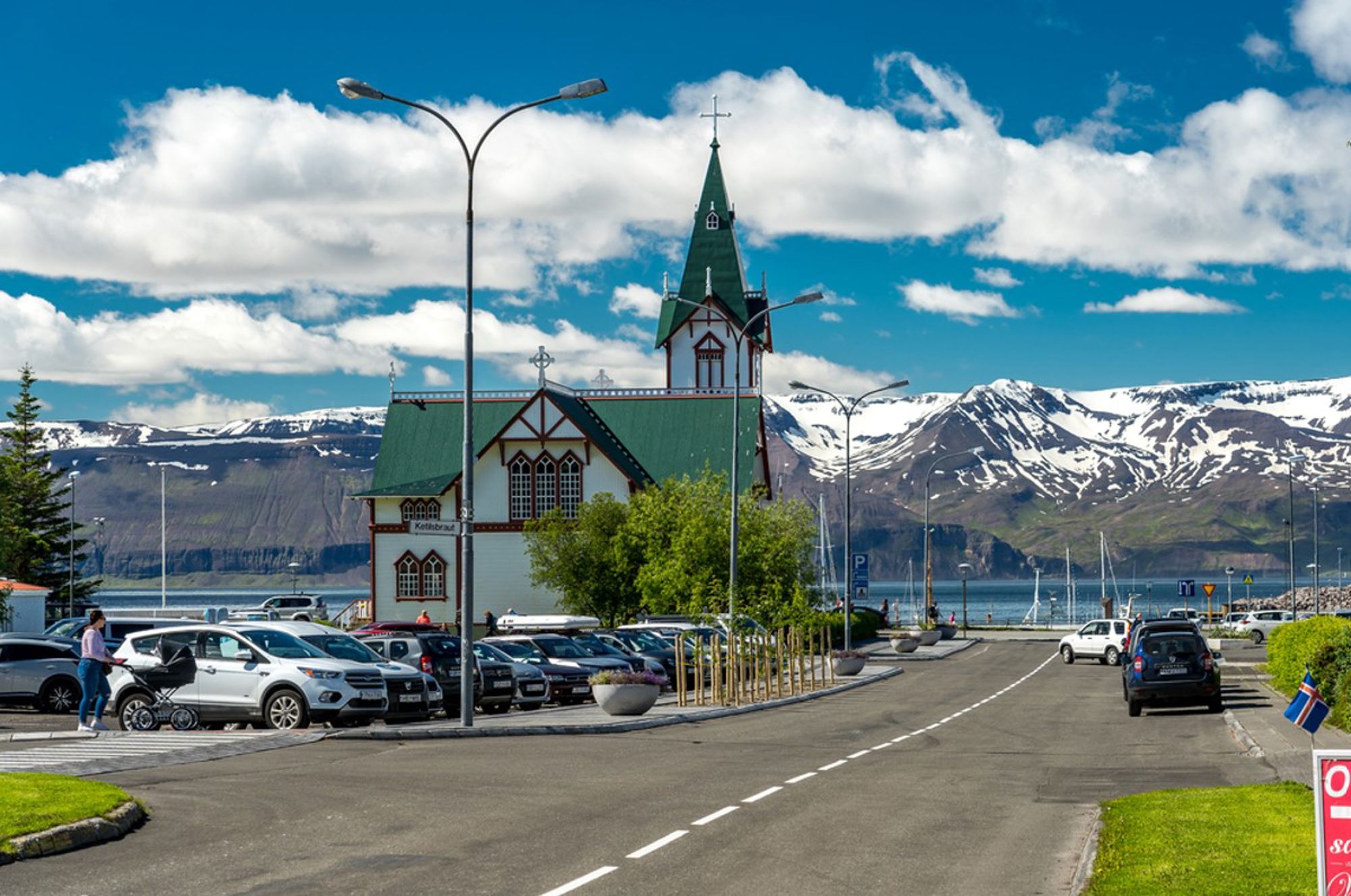 Kerk van Akureyri met groen dak aan het fjord, met besneeuwde bergen op de achtergrond.