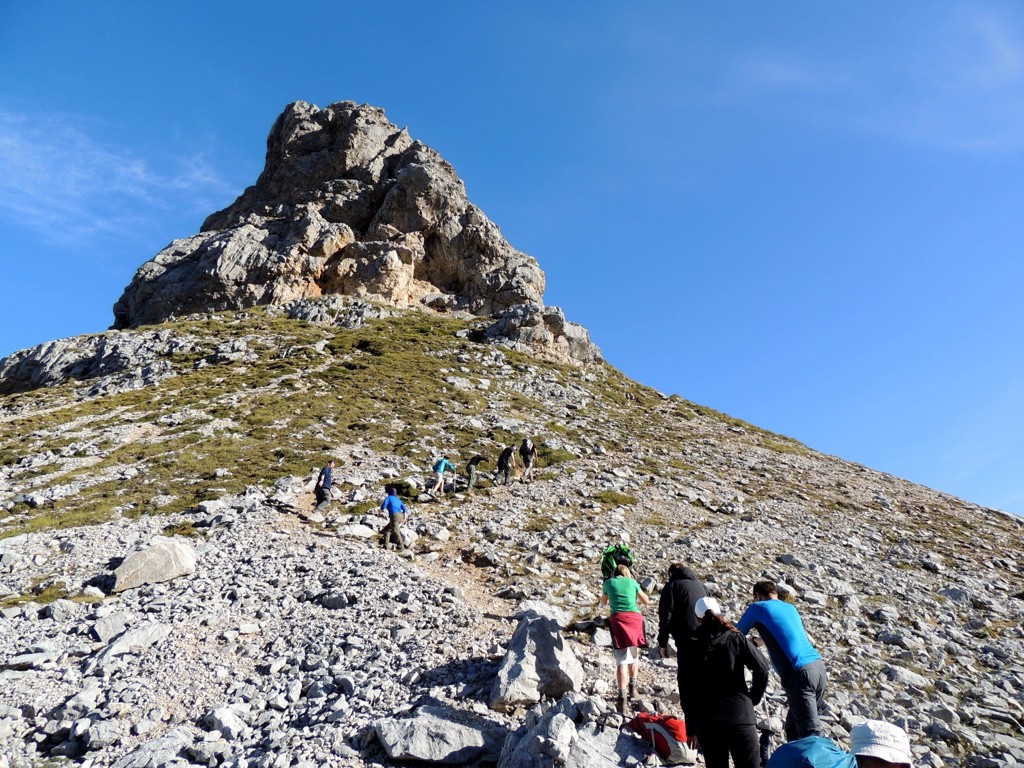Wandelaars klimmen over een rotsachtig pad naar een bergtop in de Picos de Europa, Spanje.