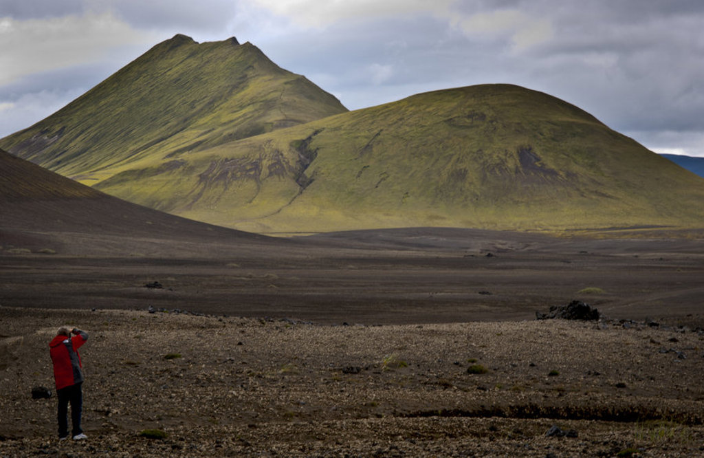 Reiziger fotografeert groen vulkanisch landschap in IJsland tijdens groepsrondreis Route IJsland.