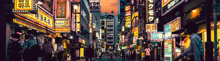 Neonverlichte straat in Tokio met drukke voetgangers en Japanse uithangborden bij zonsondergang.