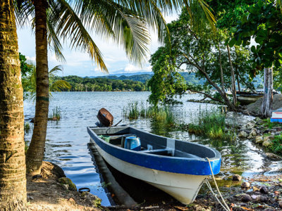 Boot aan de oever van Lago Petén Itzá, omringd door palmen en tropisch groen in Guatemala.