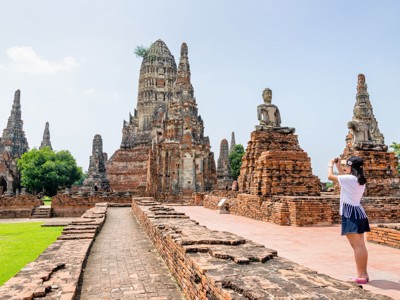 Bezoeker fotografeert tempelruïnes en Boeddhabeelden in Ayutthaya, tijdens de Route Thailand.