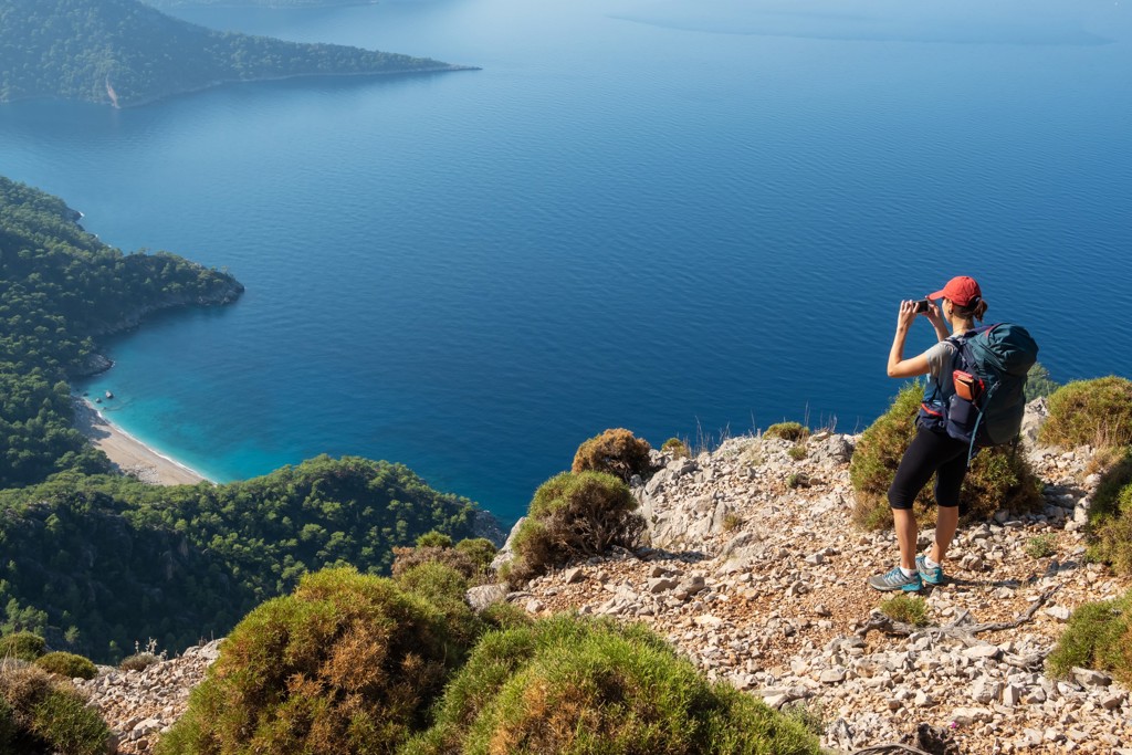 Wandelaar met rugzak kijkt uit over de Turquoise Kust in Turkije met blauwe zee en baaien.