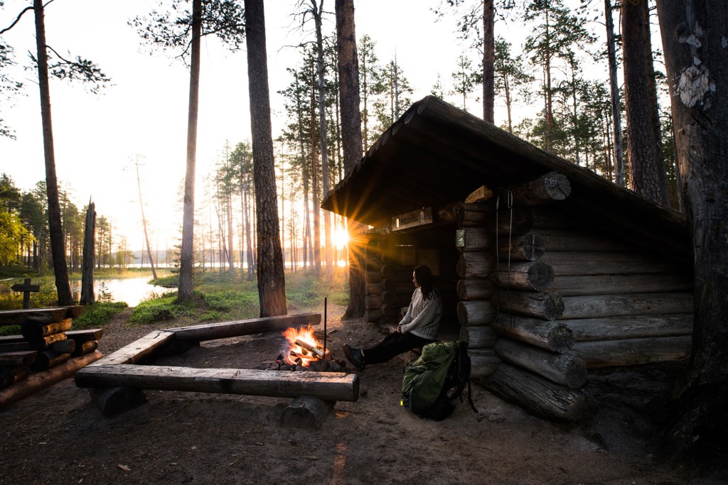Wandelen en kampvuur bij een houten hut in het bos van Lapland, Finland, tijdens een zomerse groepsrondreis.
