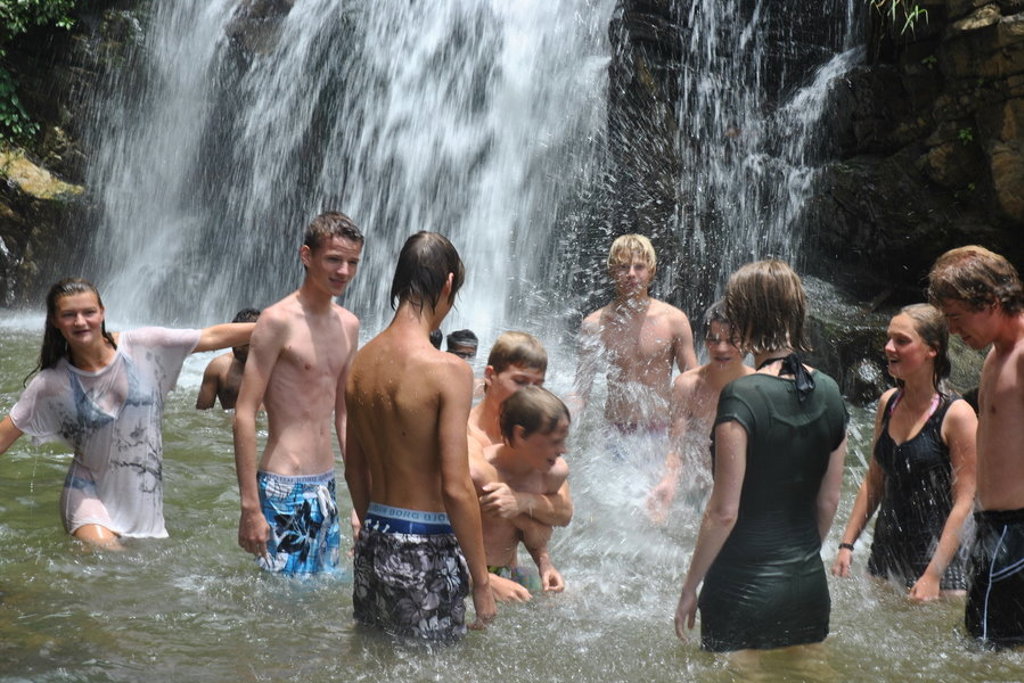 Gezin zwemt en speelt onder een waterval tijdens familiereis Sri Lanka hoogtepunten.