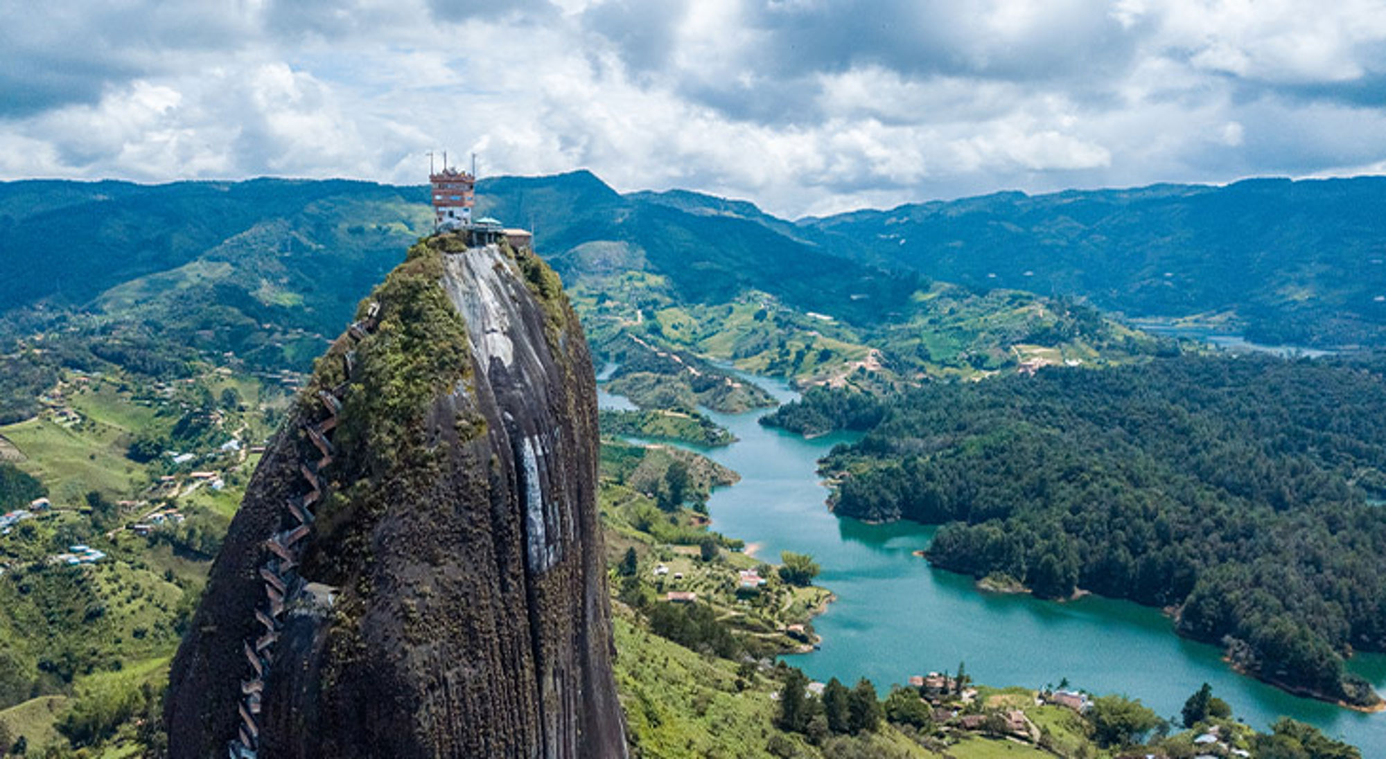 Uitzicht op El Peñón de Guatapé met trap en de turquoise stuwmeer-armen van Guatapé, Colombia.
