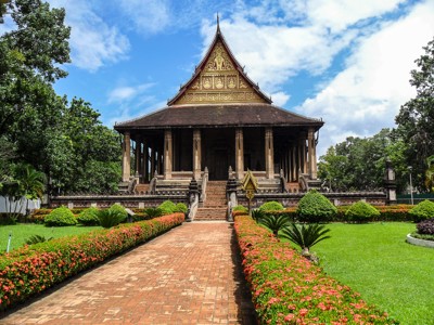 Koninklijke tempel Haw Phra Kaew in Vientiane, Laos, met tuinpad en bloemenperk.