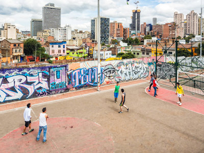 Straatbasketbal op een veld met kleurrijke graffiti en skyline van Bogotá, Colombia.
