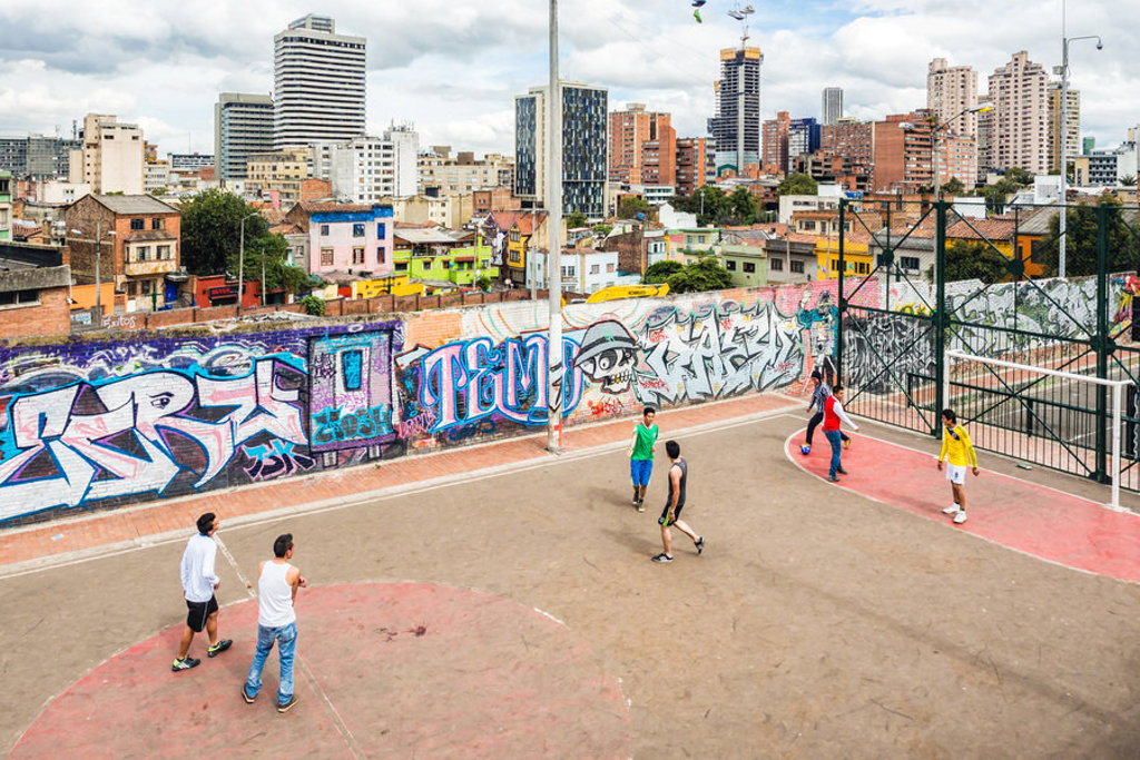 Straatbasketbal op een veld met kleurrijke graffiti en skyline van Bogotá, Colombia.