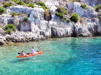 Kajakkers op helderblauw water langs de rotskust van de Turquoise Kust in Turkije.