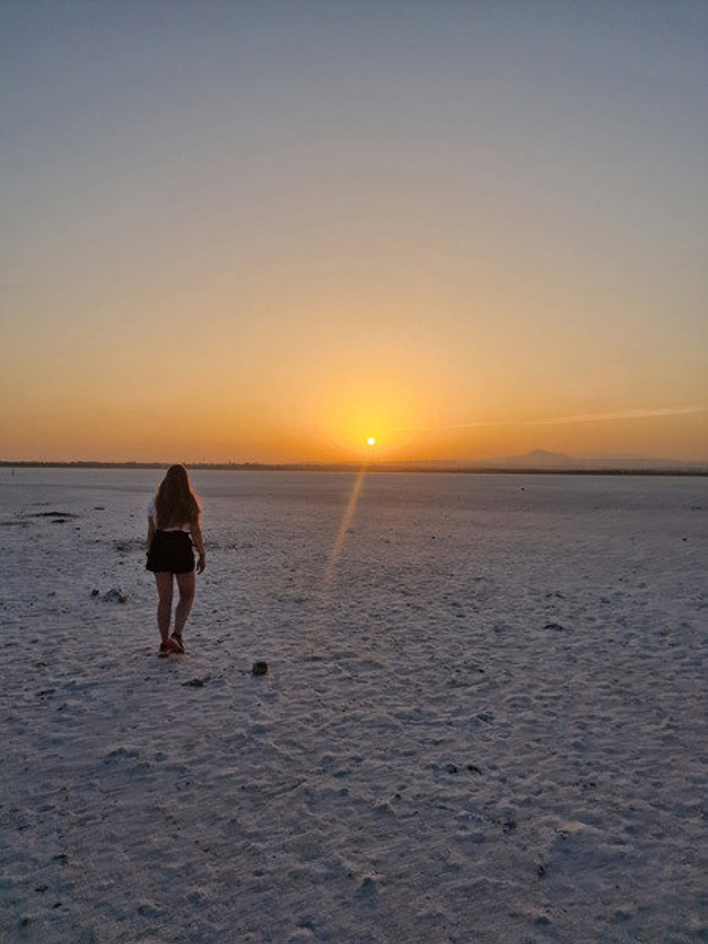 Wandelaar bij zonsondergang op de zoutvlakte van Larnaca, Cyprus.