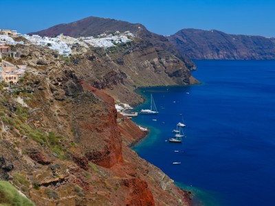 Uitzicht op de caldera van Santorini met witte huizen op de kliffen en zeilboten in de Egeïsche Zee.