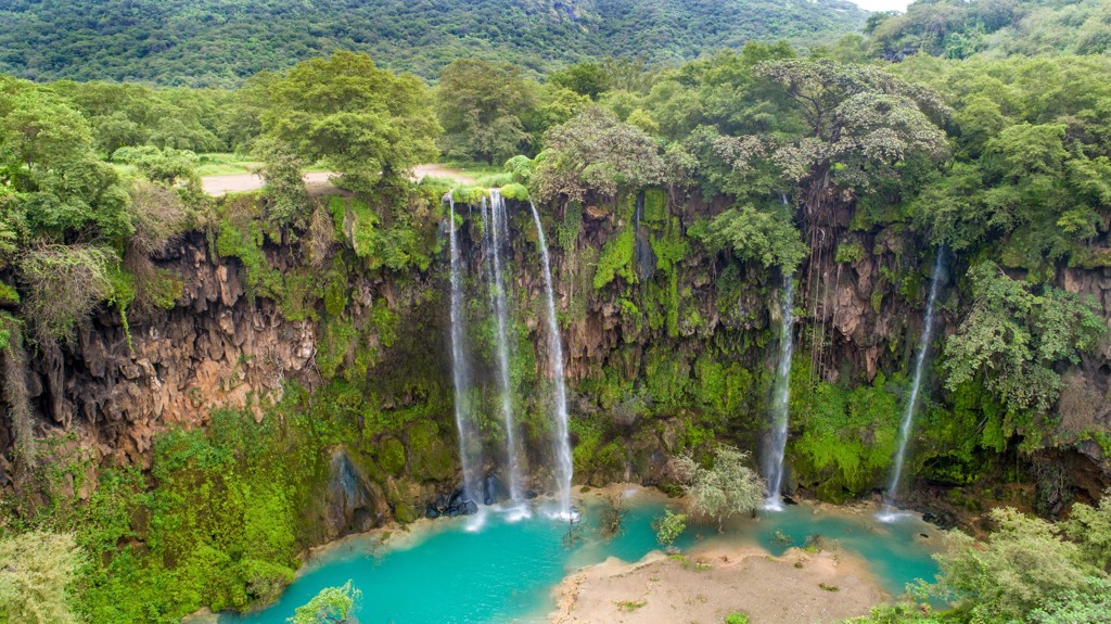 Waterval in een groene kloof met turquoise water, tijdens de groepsrondreis Oman en Dubai.