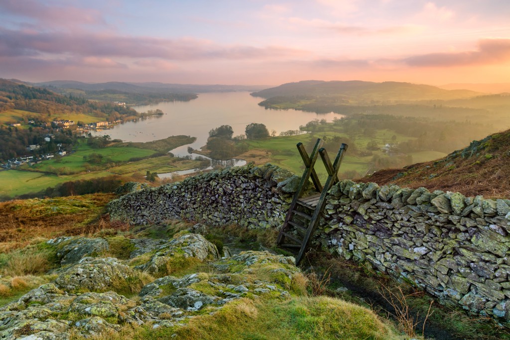 Uitzicht over Lake District met stenen muurtje en houten trapje bij zonsondergang, tijdens groepsrondreis Verenigd Koninkrijk.