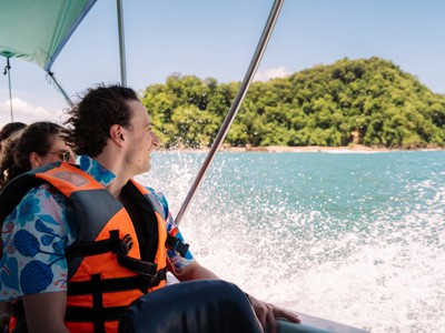 Jongvolwassenen met reddingsvest varen per boot langs de groene kust van Costa Rica.