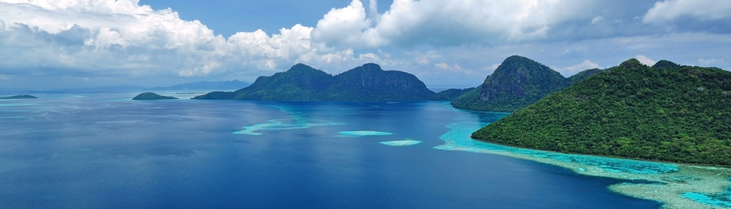 Groene eilanden en turquoise koraalriffen in zee bij Maleisisch Borneo tijdens groepsrondreis.