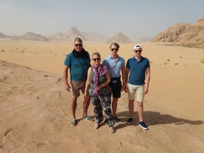 Reizigers poseren in de Wadi Rum-woestijn in Jordanië, met zandduinen en rotsbergen op de achtergrond.