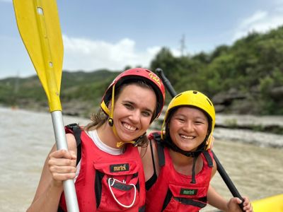 Twee reizigers met helmen en reddingsvesten in een raft op een rivier in Albanië.