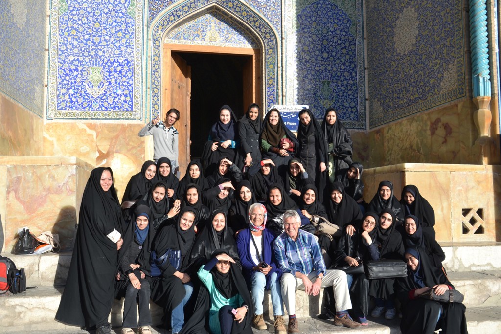 Groepsfoto van reizigers bij een kleurrijke, betegelde moskee-ingang tijdens een rondreis door Iran.