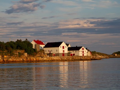 Witte vissershuisjes met rode deuren aan het water op de Lofoten in Noorwegen, bij avondlicht.