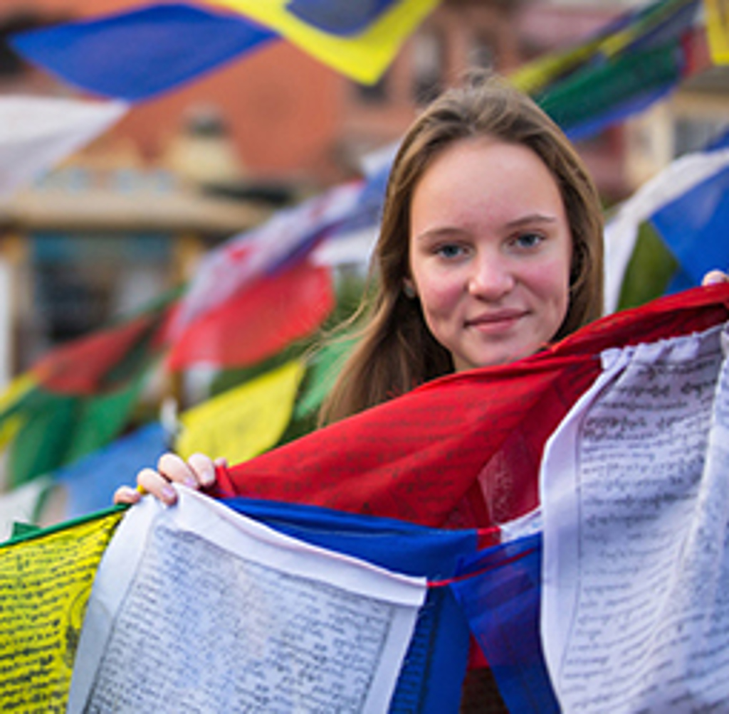 Meisje bij kleurrijke gebedsvlaggen tijdens familiereis Nepal.